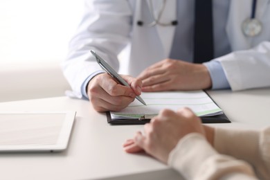 Photo of Professional doctor working with patient at white table in hospital, closeup