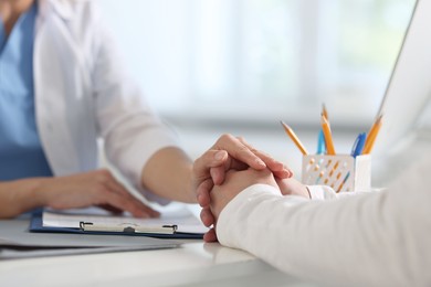 Photo of Professional doctor working with patient at white table in hospital, closeup