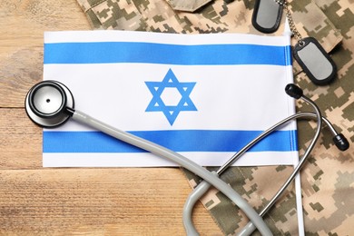 Stethoscope, flag of Israel, tags and military uniform on wooden table, flat lay