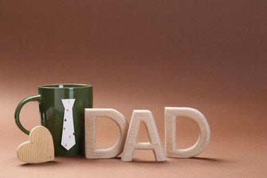 Photo of Happy Father's Day. Coffee in cup and word Dad made of wooden letters on brown background
