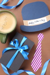 Photo of Paper hat with phrase Happy Father's Day, coffee and gift on brown background, flat lay