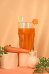 Photo of Fresh carrot juice in glass and vegetable on coral background