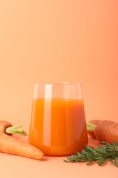 Photo of Fresh carrot juice in glass and vegetables on coral background