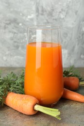 Photo of Fresh carrot juice in glass and vegetables on textured table