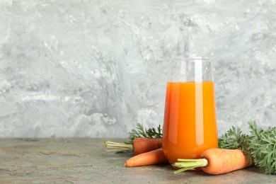 Photo of Fresh carrot juice in glass and vegetables on textured table. Space for text