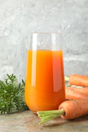 Fresh carrot juice in glass and vegetables on textured table