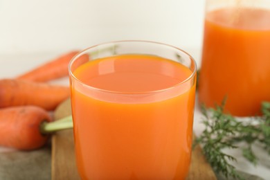 Photo of Fresh carrot juice and vegetables on light table, closeup