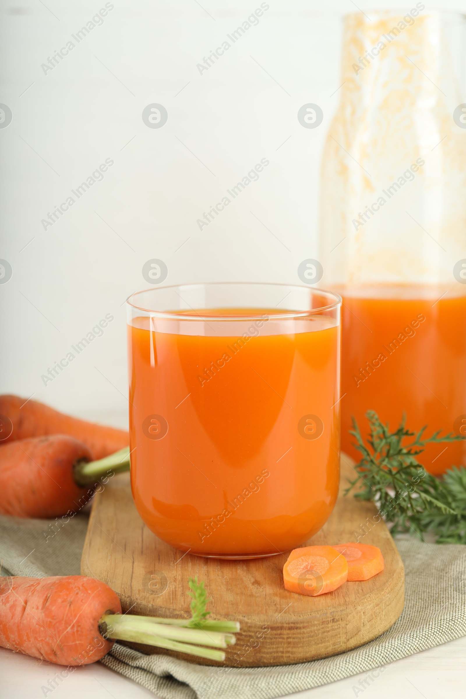 Photo of Fresh carrot juice and vegetables on light table