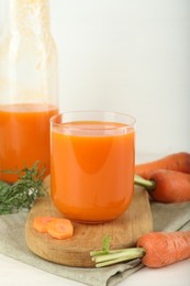Photo of Fresh carrot juice and vegetables on light table