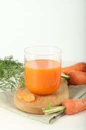 Photo of Fresh carrot juice in glass and vegetables on light table