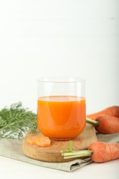 Photo of Fresh carrot juice in glass and vegetables on light table