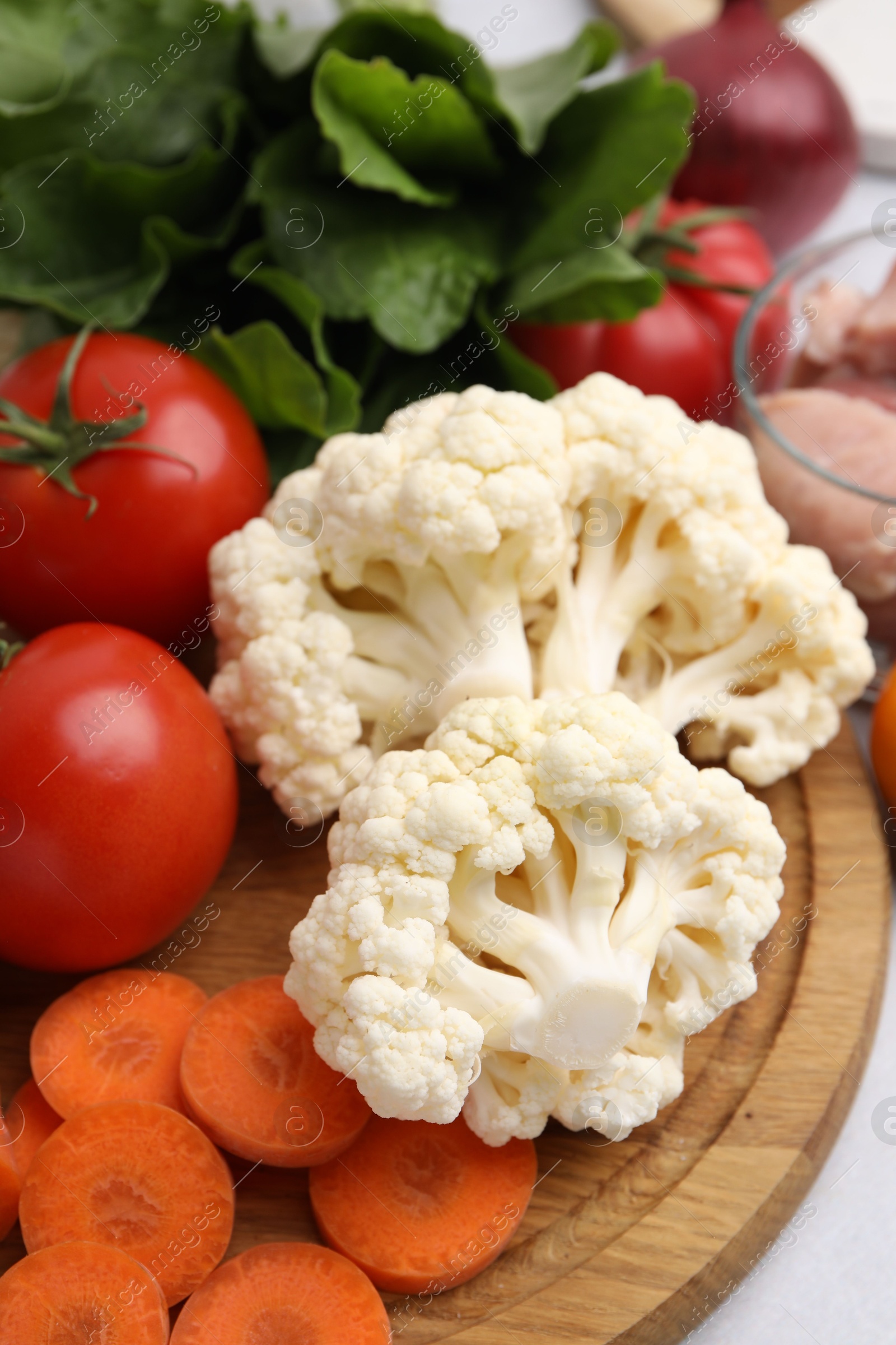 Photo of Cooking tasty stew. Cauliflower, tomatoes, carrot and spinach on table