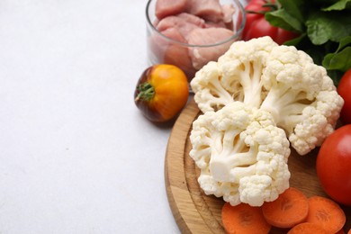 Photo of Cooking tasty stew. Cauliflower, tomatoes, carrot and raw meat on light grey table, space for text