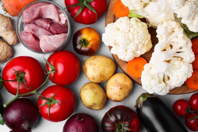 Different vegetables and raw meat for stew on light grey table, flat lay