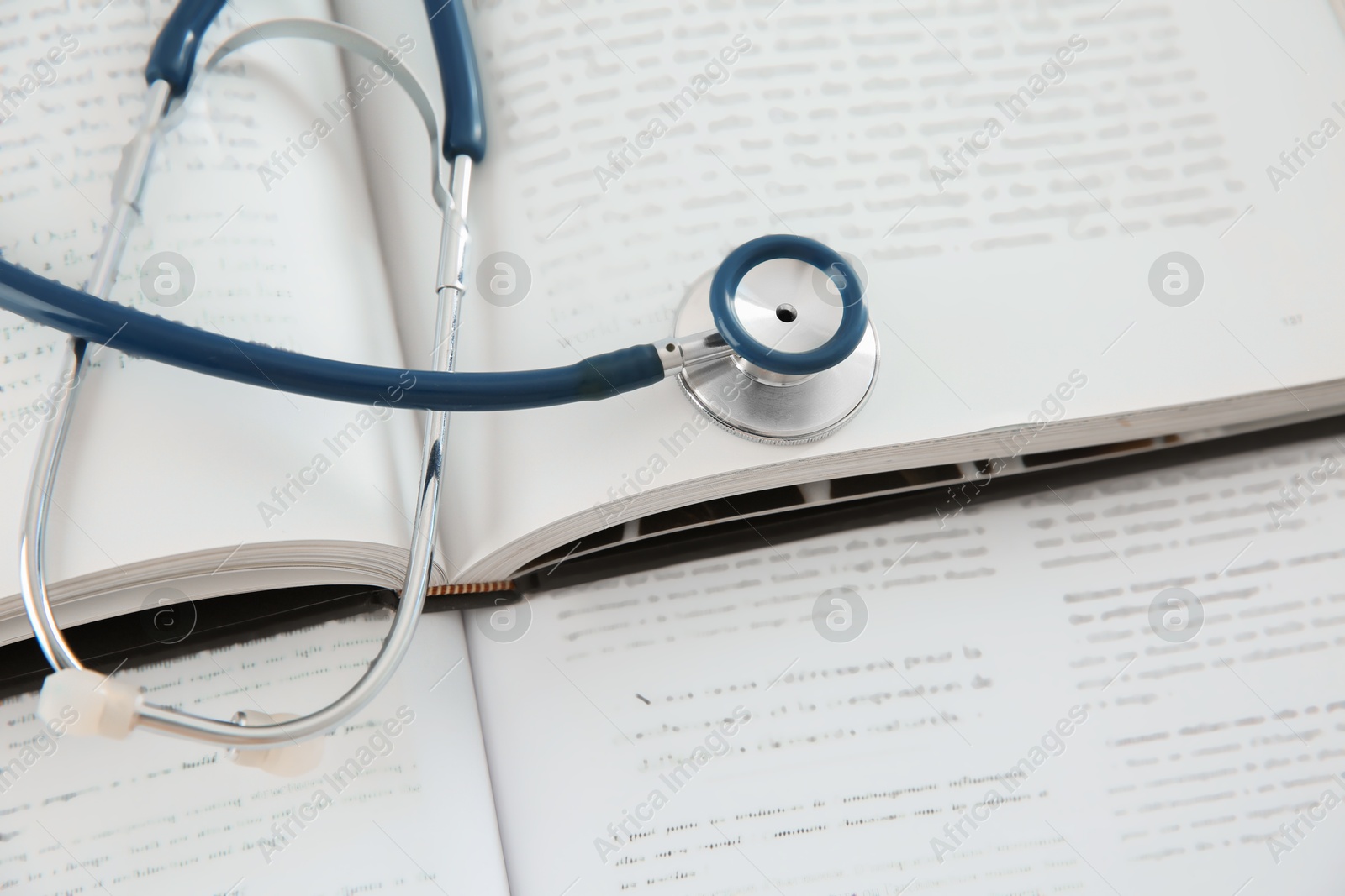 Photo of One medical stethoscope and books on table, above view