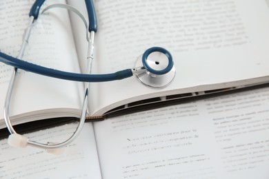 One medical stethoscope and books on table, above view