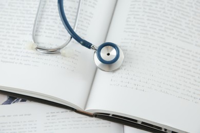 Photo of One new medical stethoscope and books on table, above view