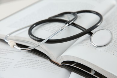 One medical stethoscope and books on table, closeup