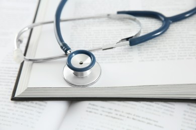 Photo of One new medical stethoscope and books on table, closeup