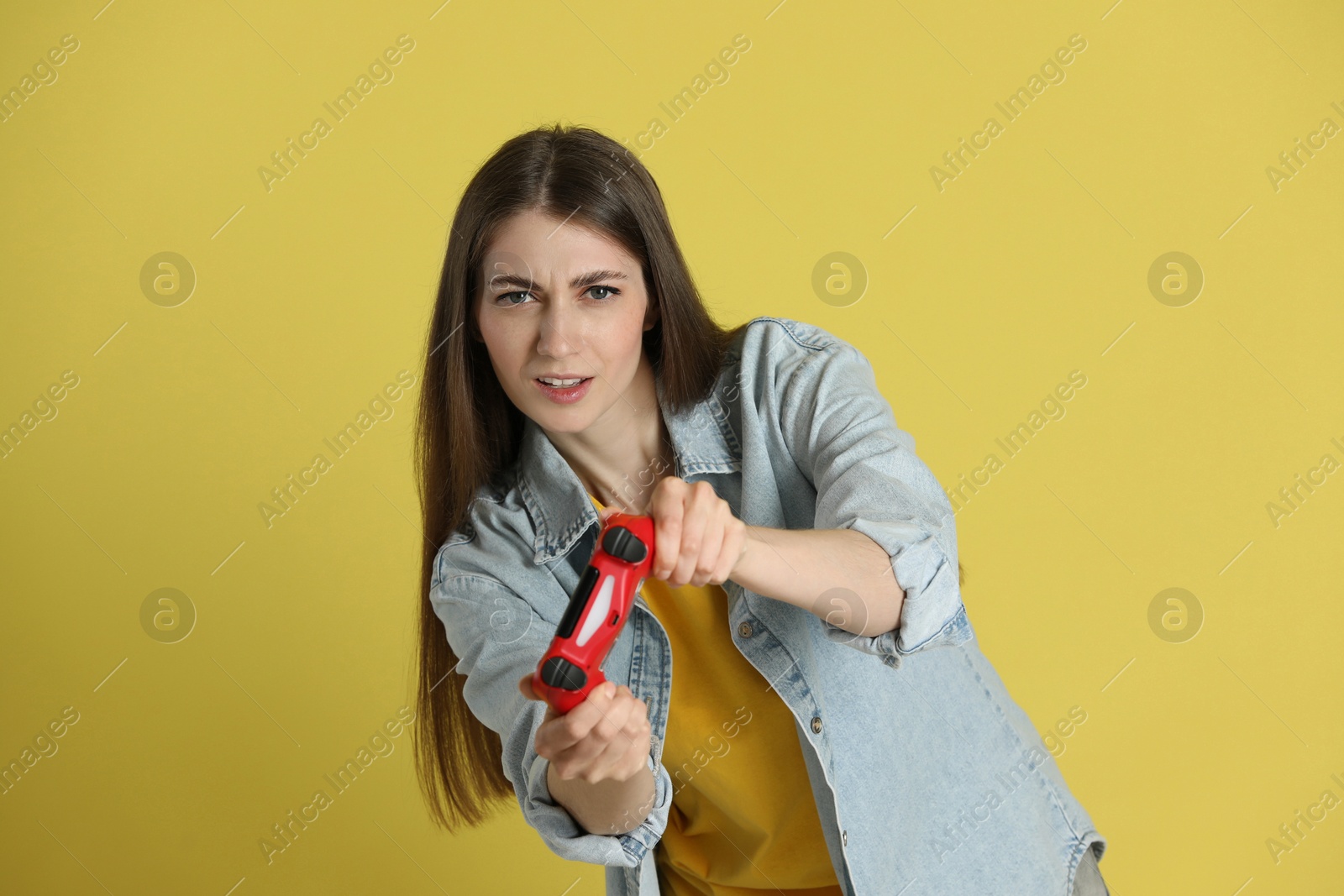 Photo of Woman playing video games with controller on yellow background