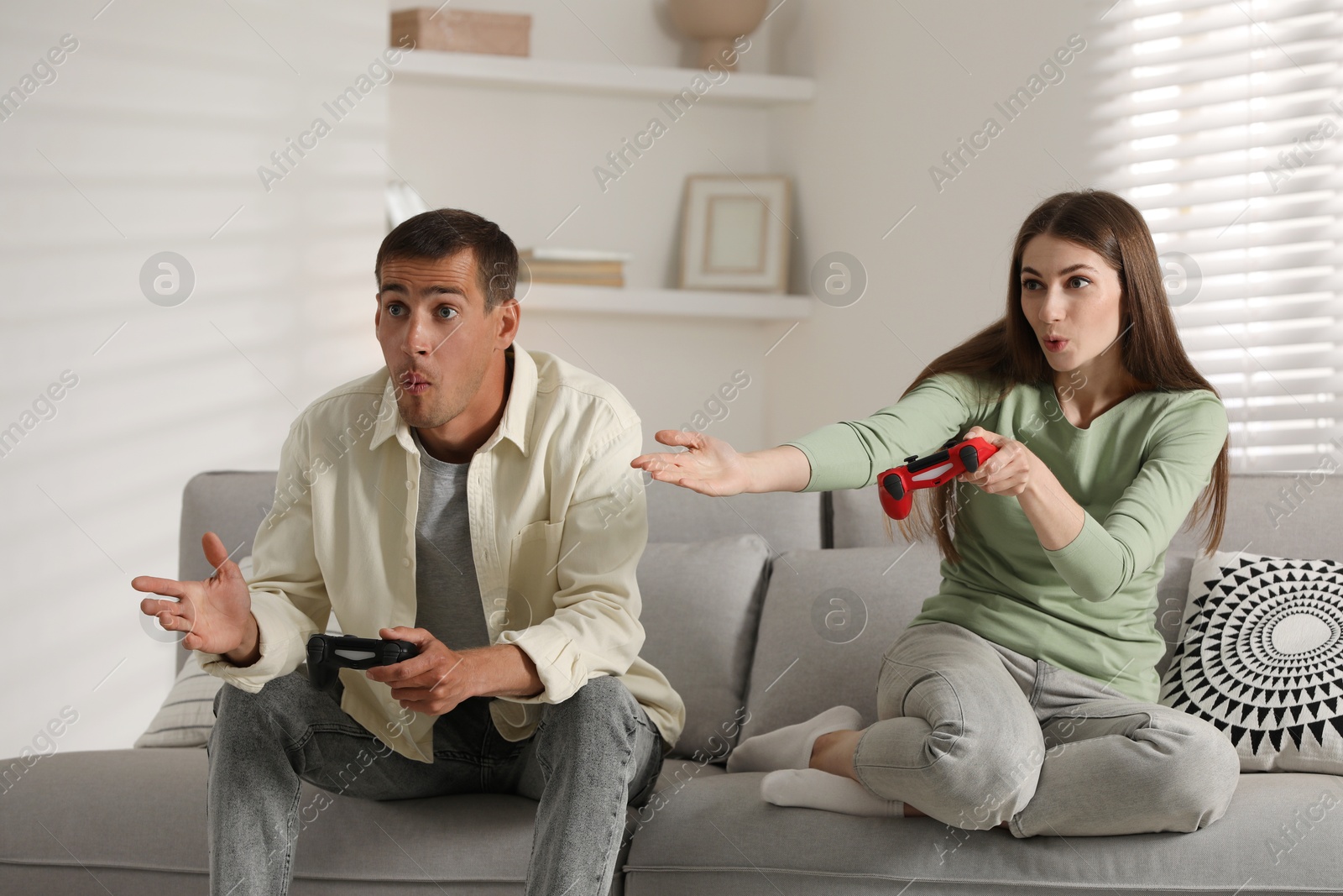 Photo of Couple playing video games with controllers at home