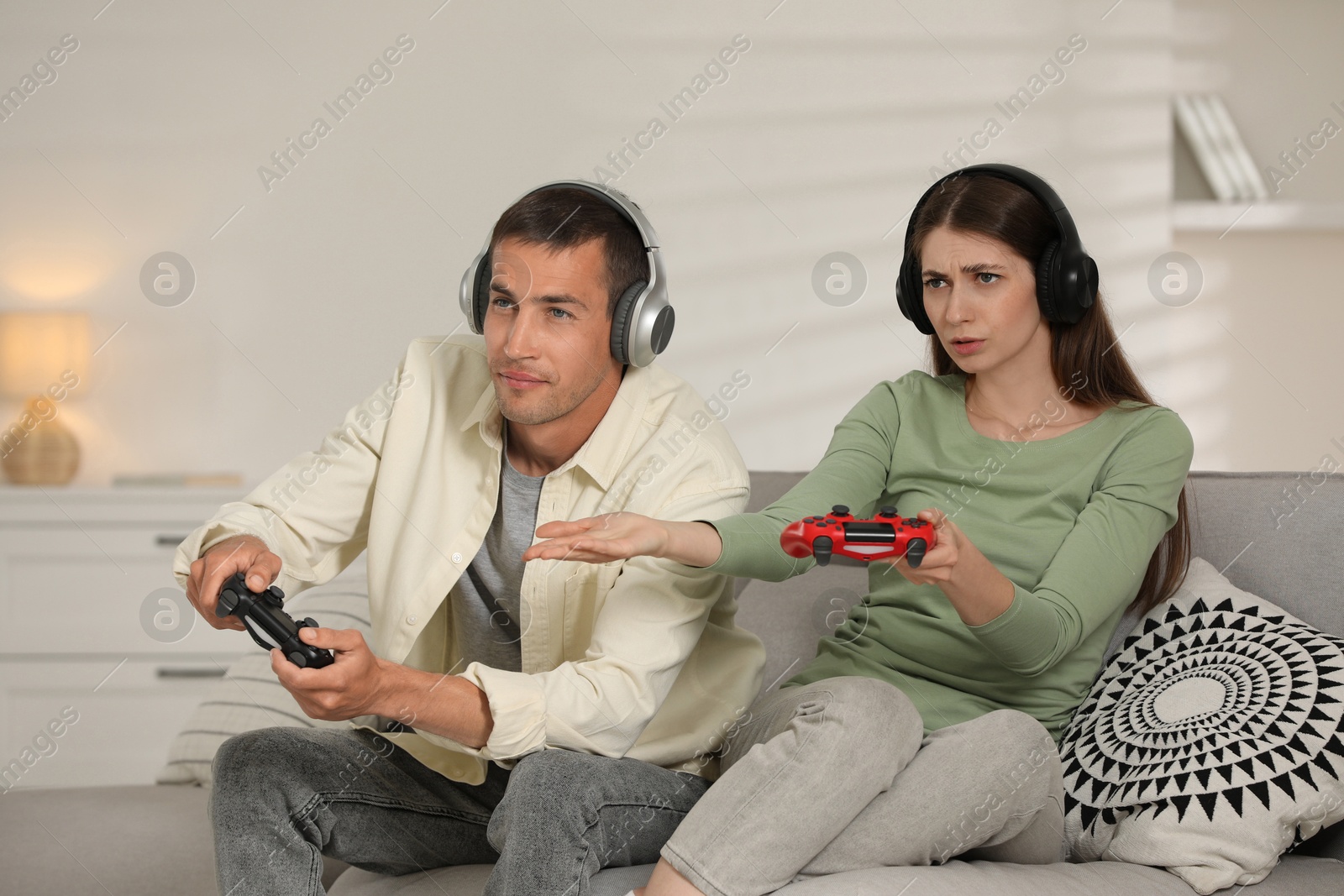 Photo of Couple playing video games with controllers at home