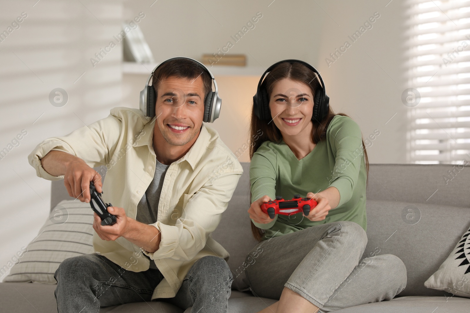 Photo of Couple playing video games with controllers at home