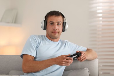 Photo of Man in headphones playing video games with joystick at home