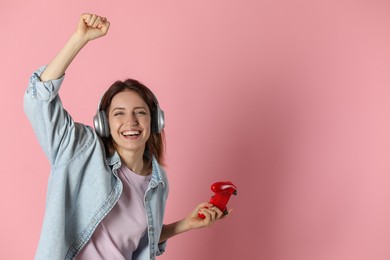 Photo of Happy woman in headphones with game controller on pink background. Space for text