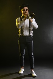 Photo of Professional musician playing trumpet on black background in color lights