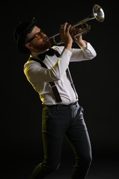 Photo of Professional musician playing trumpet on black background in color lights