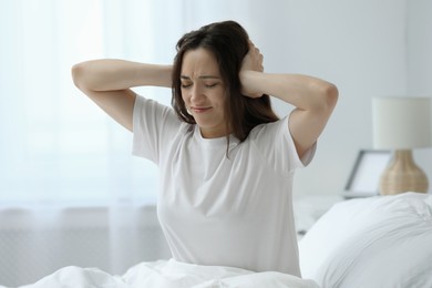 Photo of Woman covering ears in bed at home