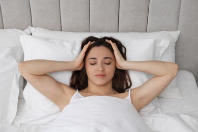 Woman suffering from headache in bed indoors