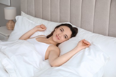 Photo of Smiling woman lying in bed at home