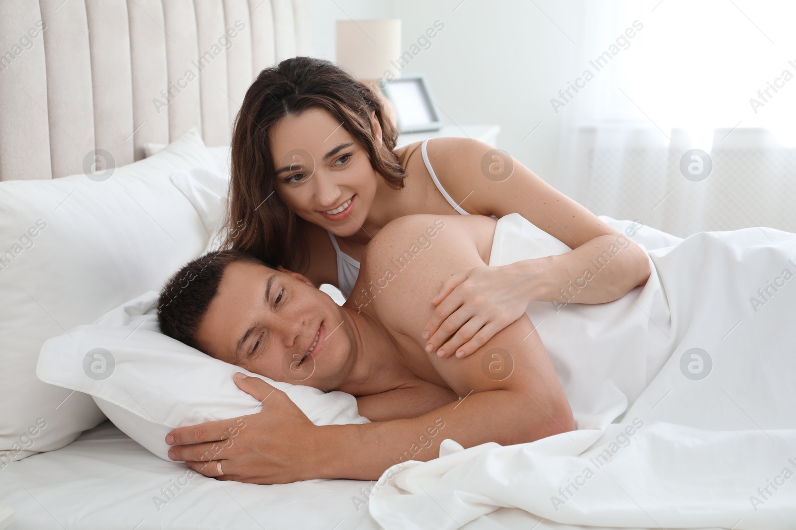 Photo of Happy couple lying in bed at home