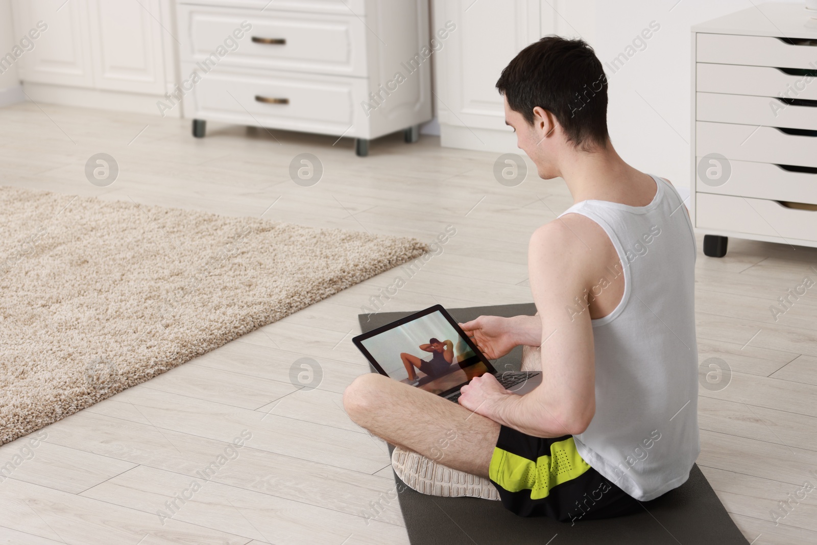 Photo of Online fitness trainer. Man watching tutorial on laptop indoors