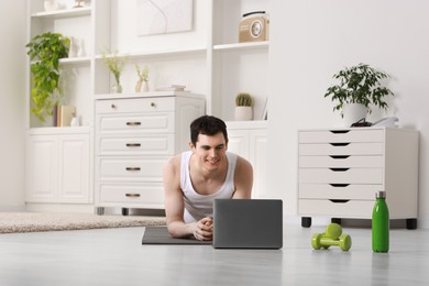 Photo of Online fitness trainer. Man watching tutorial on laptop indoors