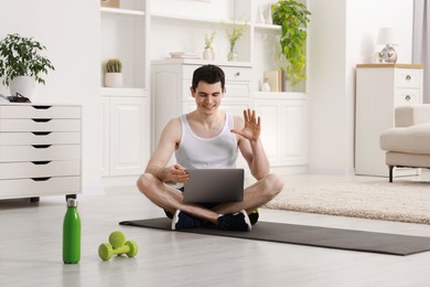 Online fitness trainer. Man having video chat via laptop at home