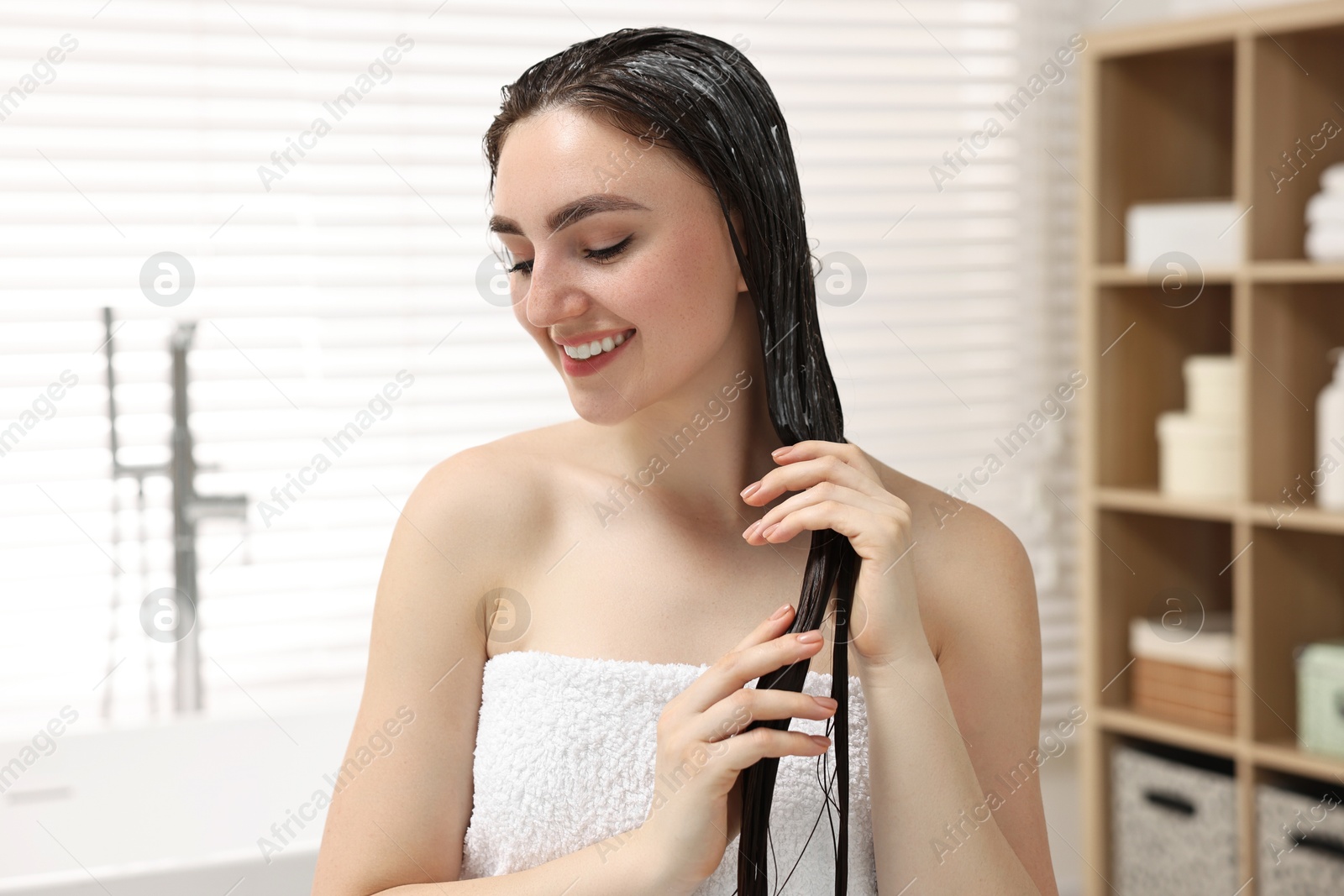 Photo of Smiling woman with applied hair mask in bathroom