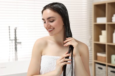 Photo of Smiling woman with applied hair mask in bathroom