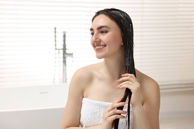 Photo of Smiling woman with applied hair mask in bathroom. Space for text