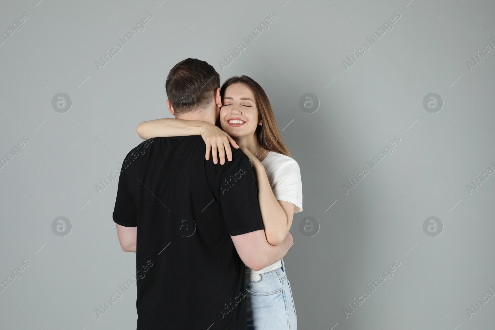 Photo of Smiling woman hugging her boyfriend on grey background. Space for text