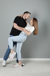 Photo of Happy couple hugging near grey wall. Strong relationship