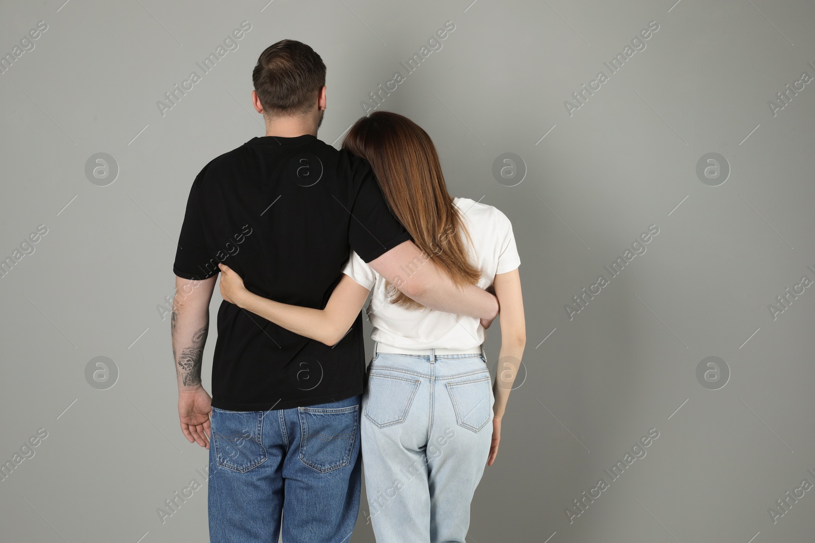 Photo of Cute couple hugging on grey background, back view. Space for text