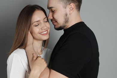 Man hugging and kissing his happy girlfriend on grey background