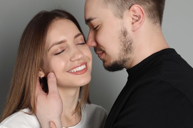 Photo of Man hugging and kissing his happy girlfriend on grey background