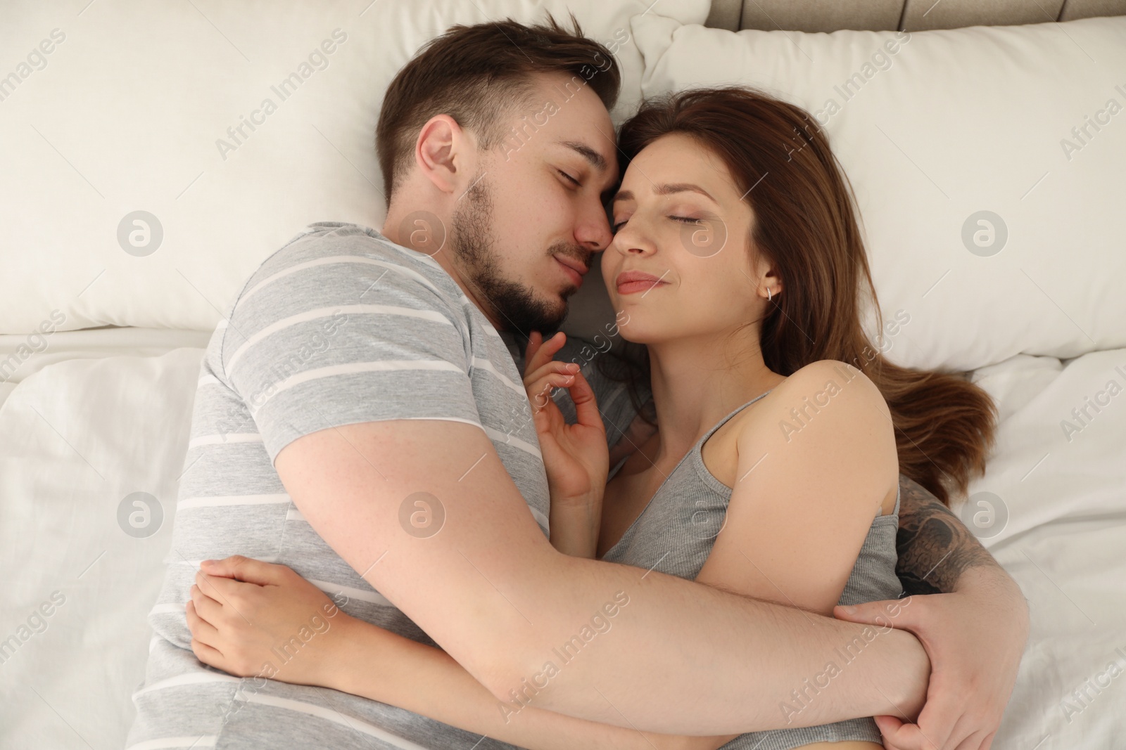 Photo of Man hugging his girlfriend on bed at home