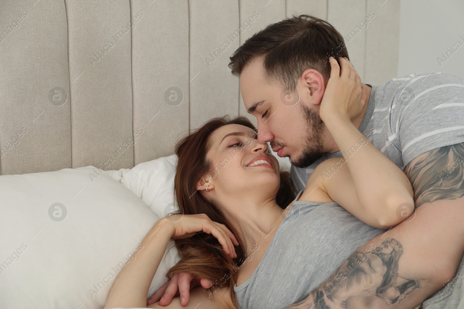 Photo of Lovely couple hugging and kissing on bed at home. Space for text