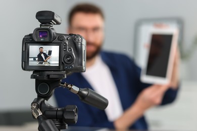 Technology blogger explaining something while recording video at home, focus on camera