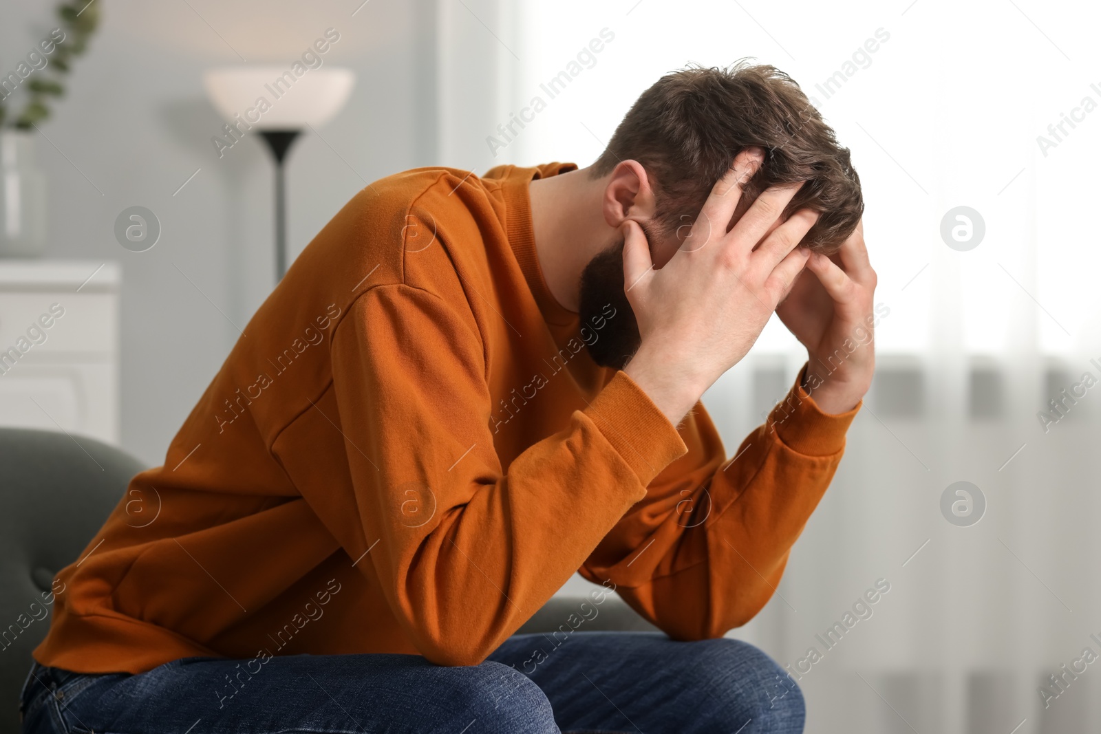 Photo of Overwhelmed man sitting on sofa at home